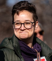 Charlie's portrait shows her outdoors, smiling, wearing a coat and glasses